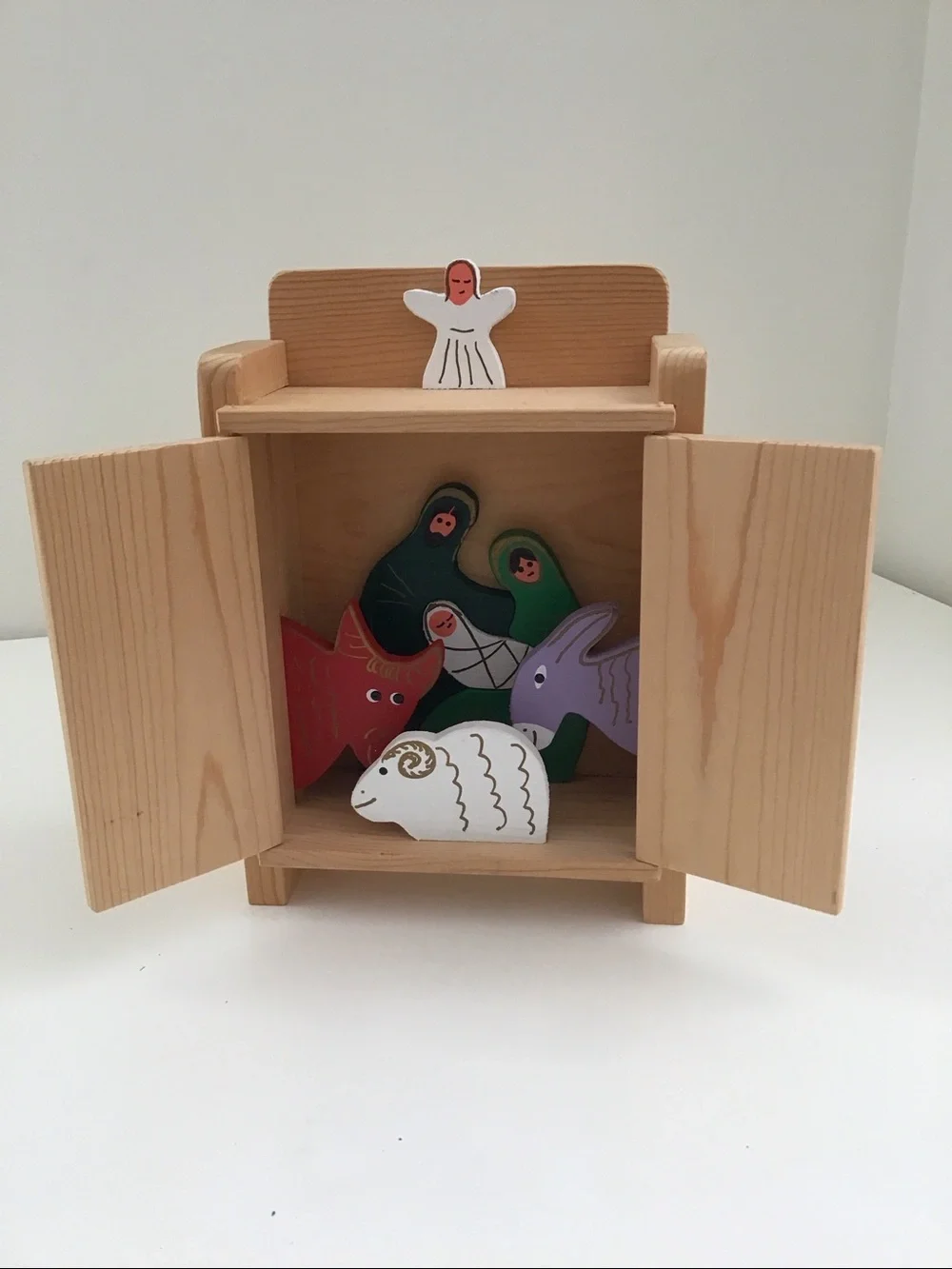 Handmade wooden cabinet holding a small wooden Nativity set